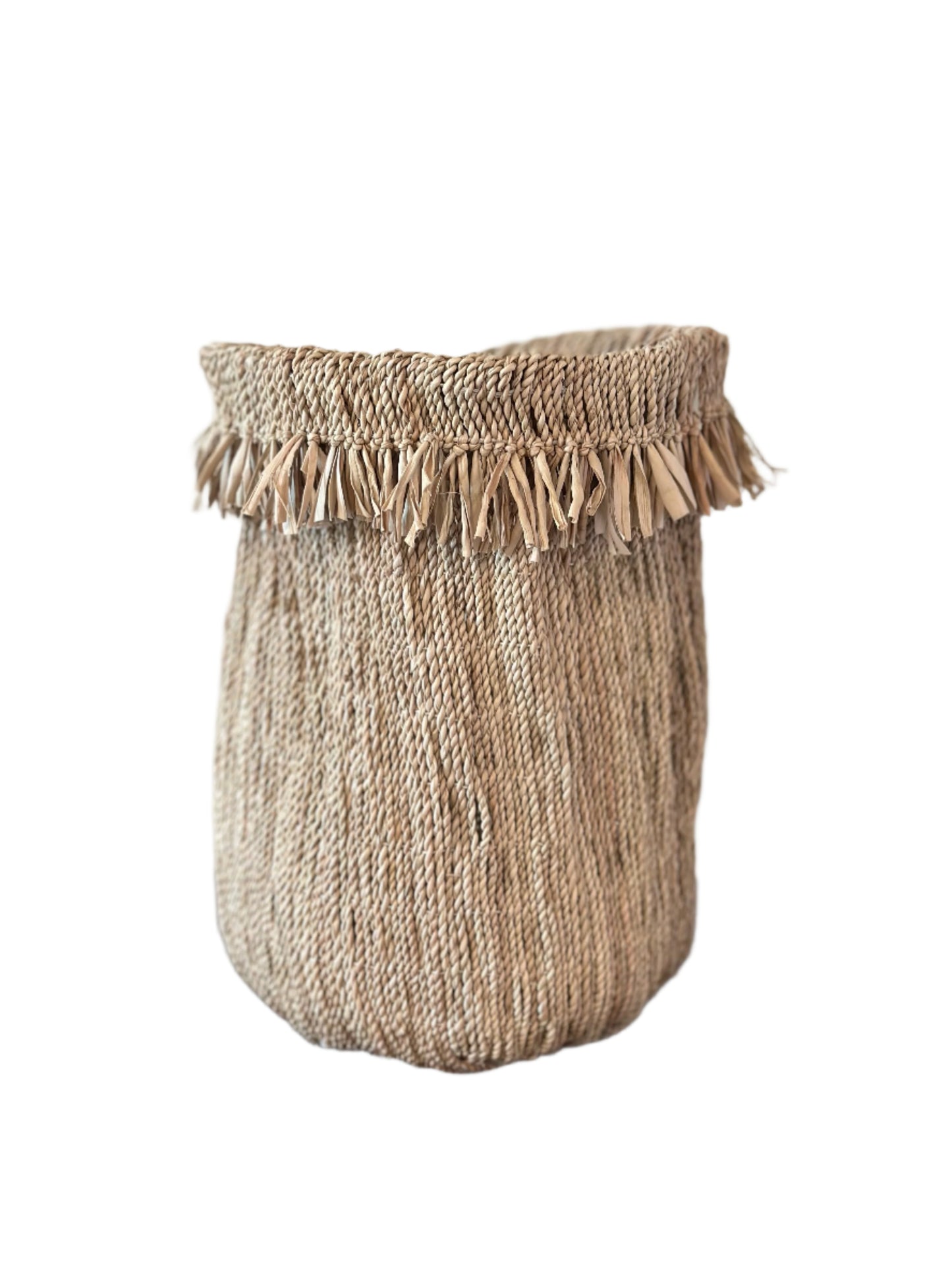 Woven basket with tassels on a wooden surface against a plain background