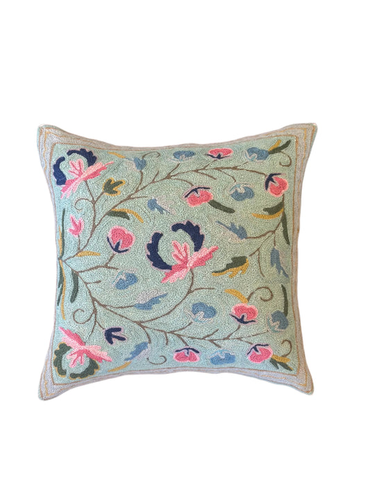 Decorative pillow with floral embroidery on a wooden surface