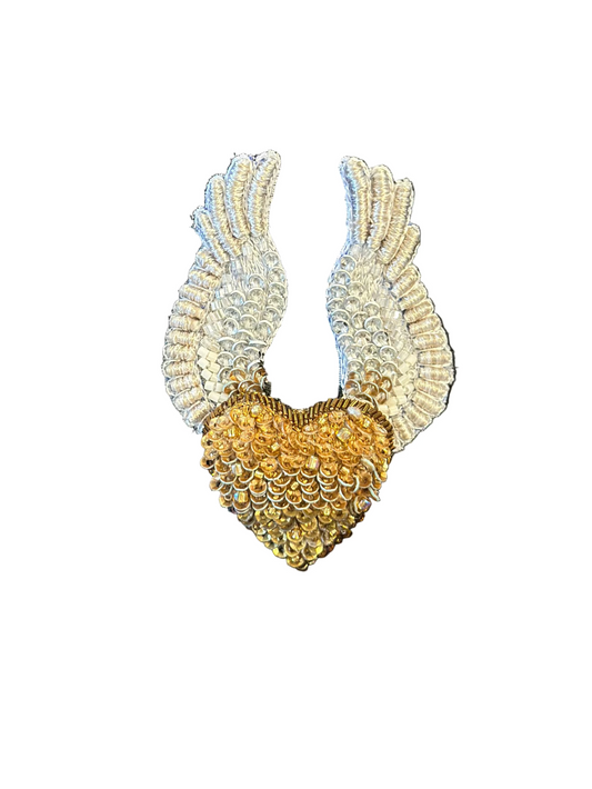 Decorative brooch with wings and a heart in a blue box on a wooden surface